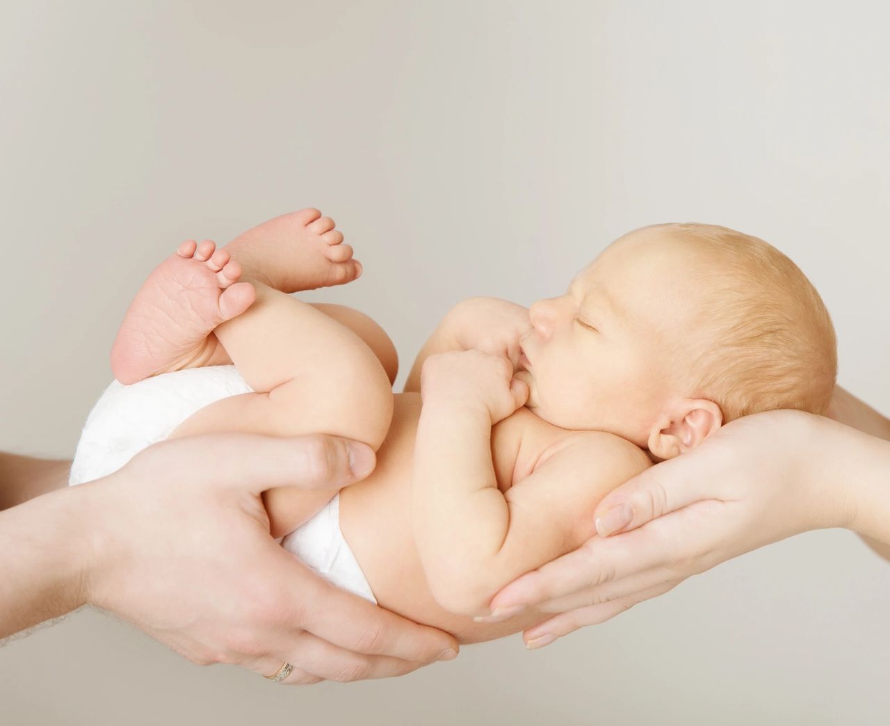 A baby cradled by parents | When is the best time to start signing with your baby